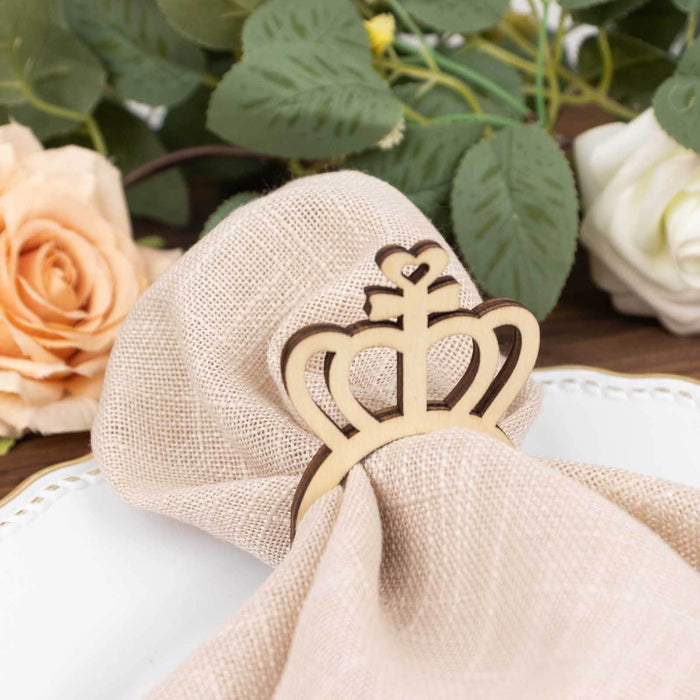 Wooden crown napkin holder with pink linen napkin and floral backdrop.