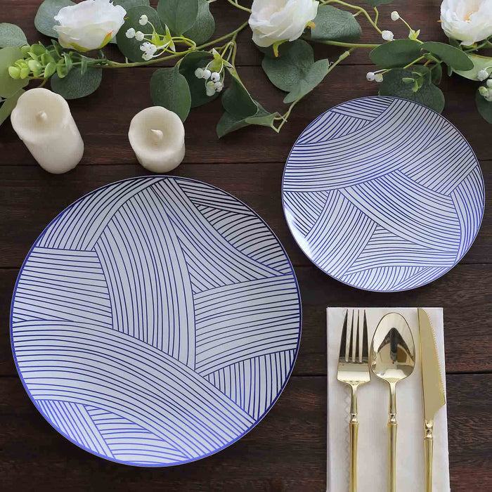 Elegant blue and white patterned plates with cutlery and candles on a wooden table.