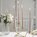 Elegant candle holder with four lit candles and floral arrangement.