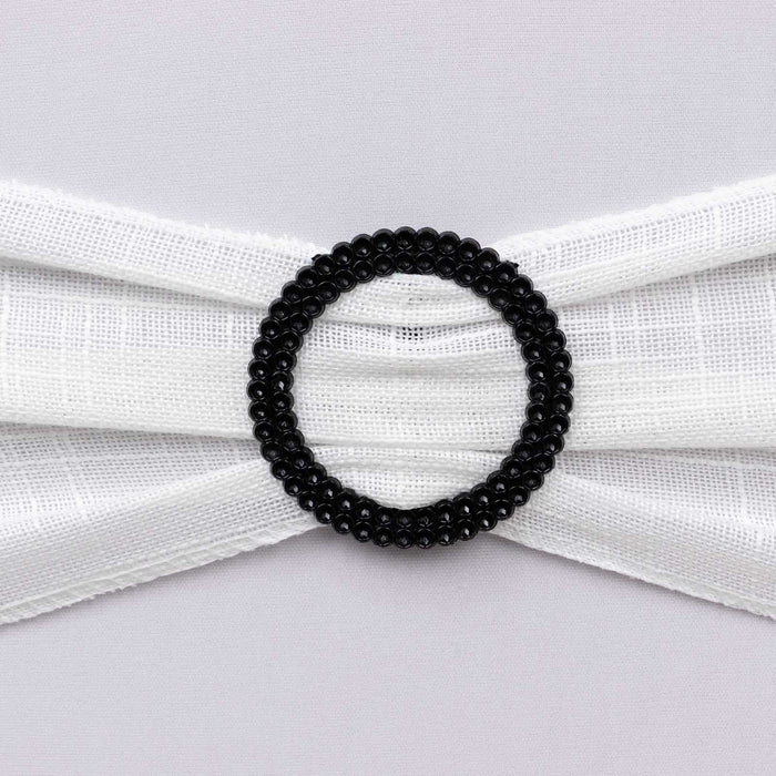 Black beaded hair accessory on white fabric background.