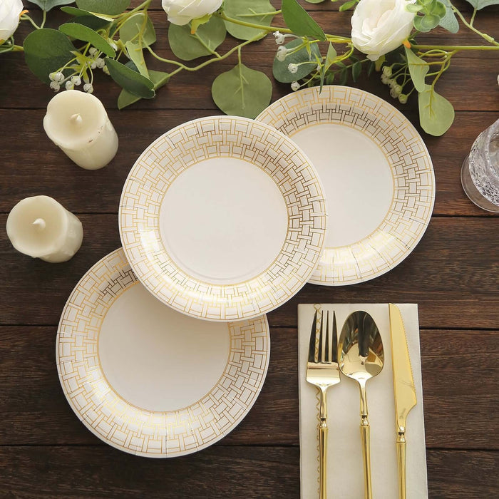 Elegant gold-accented plates arranged on a wooden table with candles and greenery.