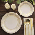Elegant gold-accented dinner plates with cutlery and candles on a wooden table.