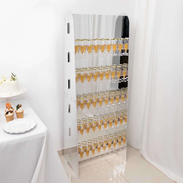 Mirrored champagne tower display with multiple rows of glasses filled with drinks.