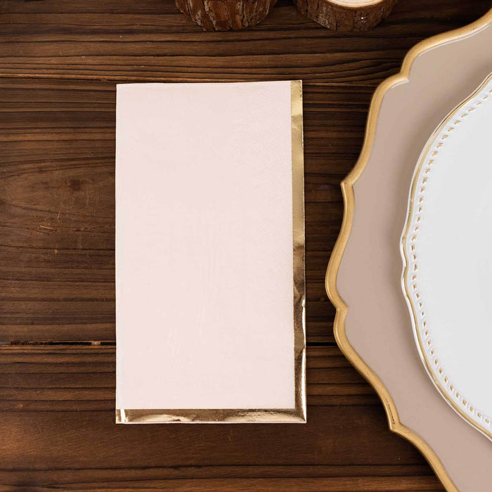 Blush pink napkin with gold foil trim on a wooden table