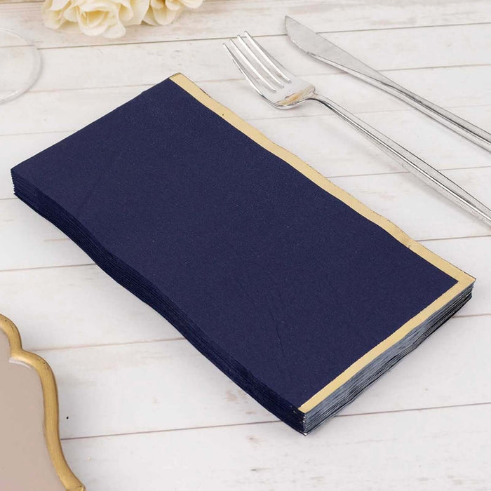Navy blue napkins with gold trim on a white table setting.