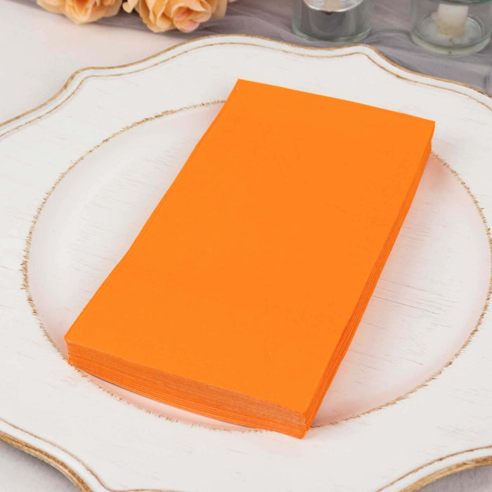 Stack of vibrant orange napkins on a decorative plate.