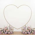 Gold heart-shaped photo backdrop with floral arrangement at the base.