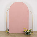 Pink arch backdrop with floral arrangements on the floor.