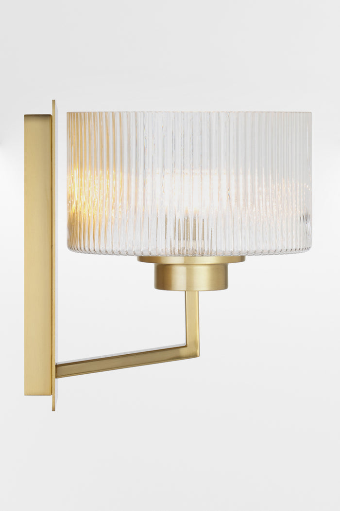 Side view of the wall sconce in Antique Gold with a rectangular mount plate and arm, holding a clear reeded cylindrical glass shade.
