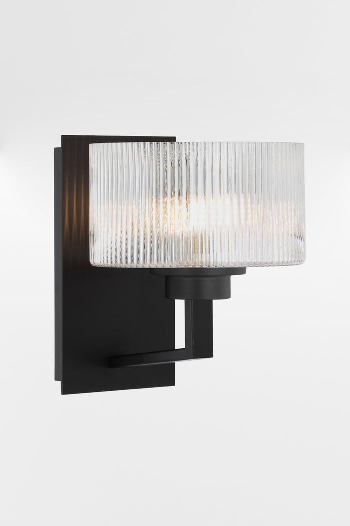 Wall sconce in black with a rectangular mount plate and arm, holding a clear reeded cylindrical glass shade.