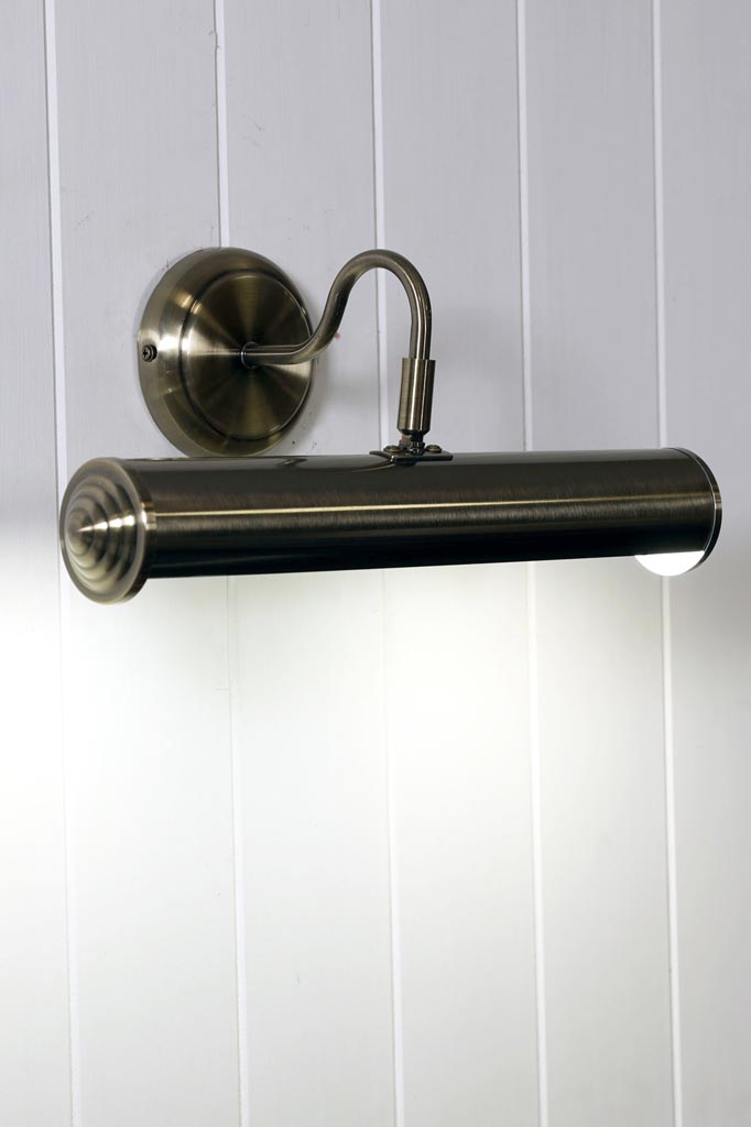 Antique Brass picture light hanging on white shiplap.