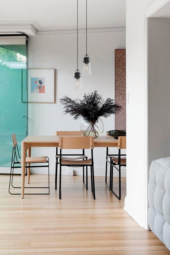 Two clear glass pendat lights with black hardware in a bright and modern dining space.