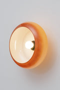 Avoca Glass Wall Light with light on attached closely to wall. Scuptual like