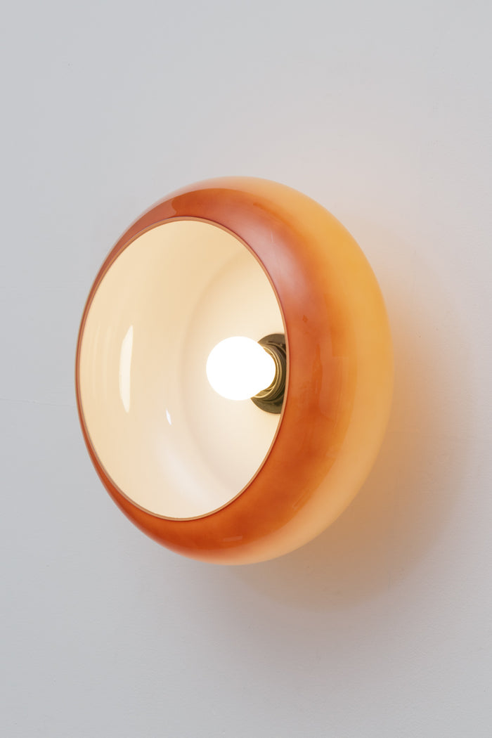 Avoca Glass Wall Light with light on attached closely to wall. Scuptual like