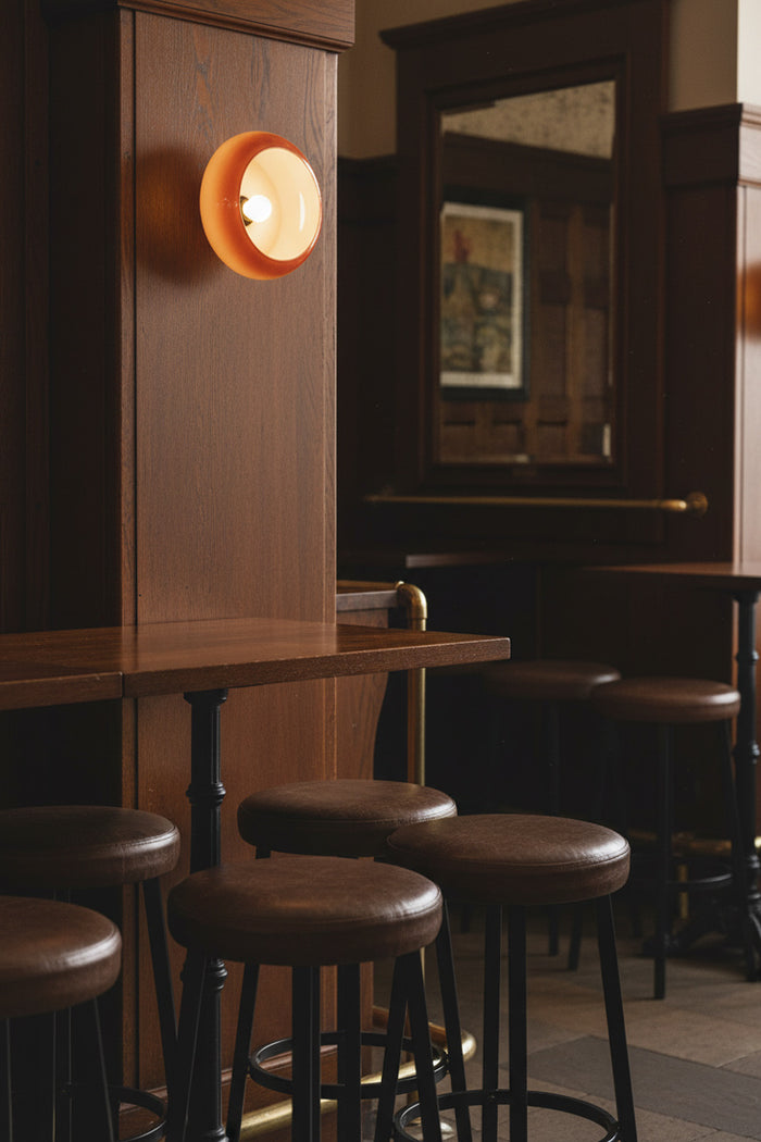 Bar area with wooden walls, stools, and avoca wall light above bar table