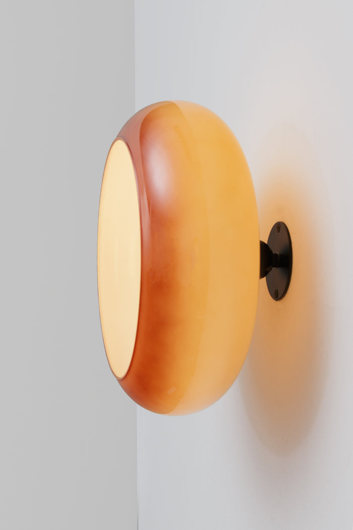Glass wall light showcasing a rich depth and luminous colour gradient that shifts at the base to a deeper, smokier tone at the rim.