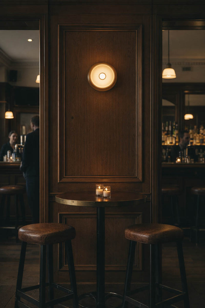 Dark bar interior with wooden panel, Avoca wall lights in sage and bar stools.