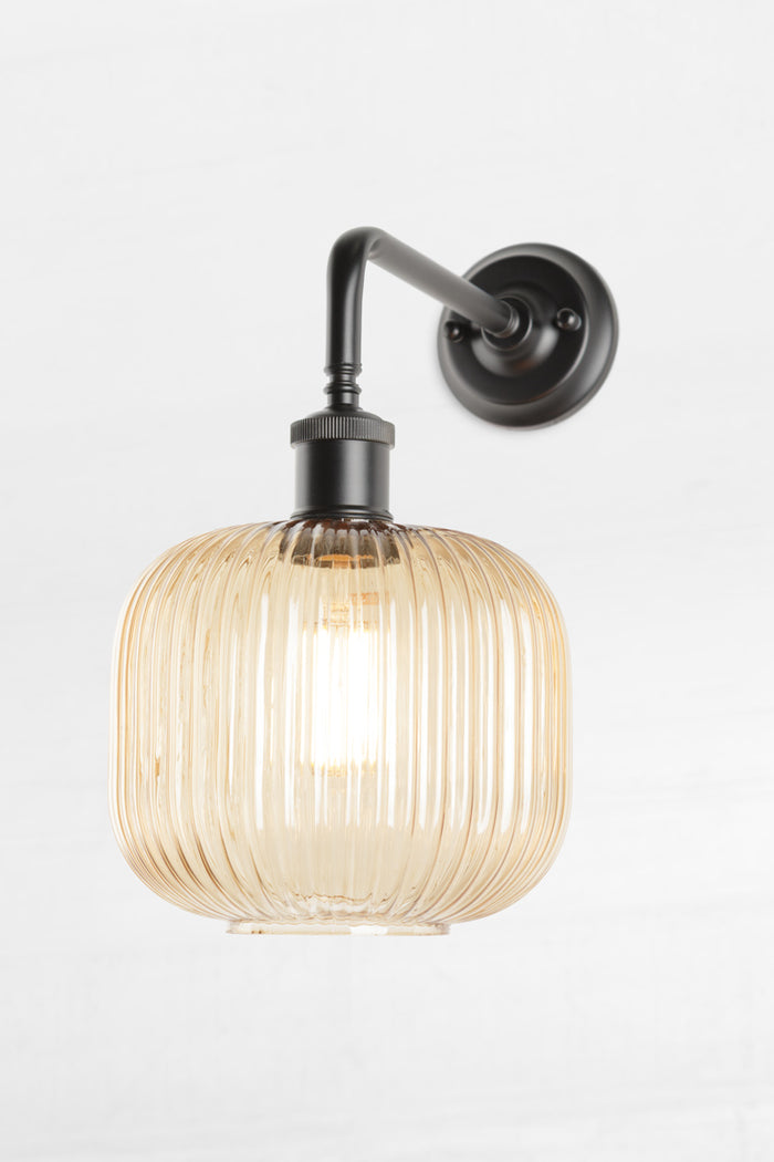 amber glass reeded shade paired with a black 90 degree wall sconce.