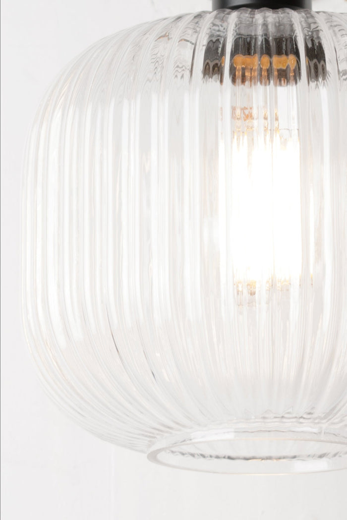 Wall-mounted light fixture with ribbed glass shade on a white background