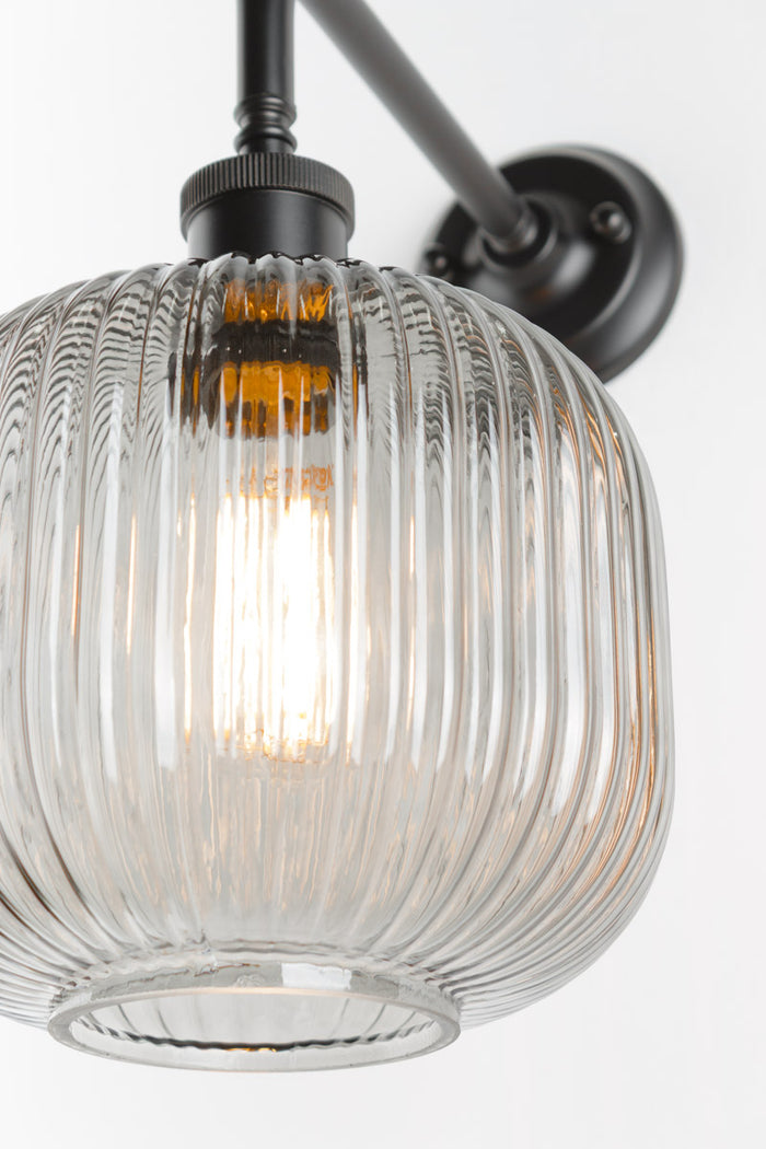 Close up of the open clear glass reeded shade paired with a black 90 degree wall sconce.