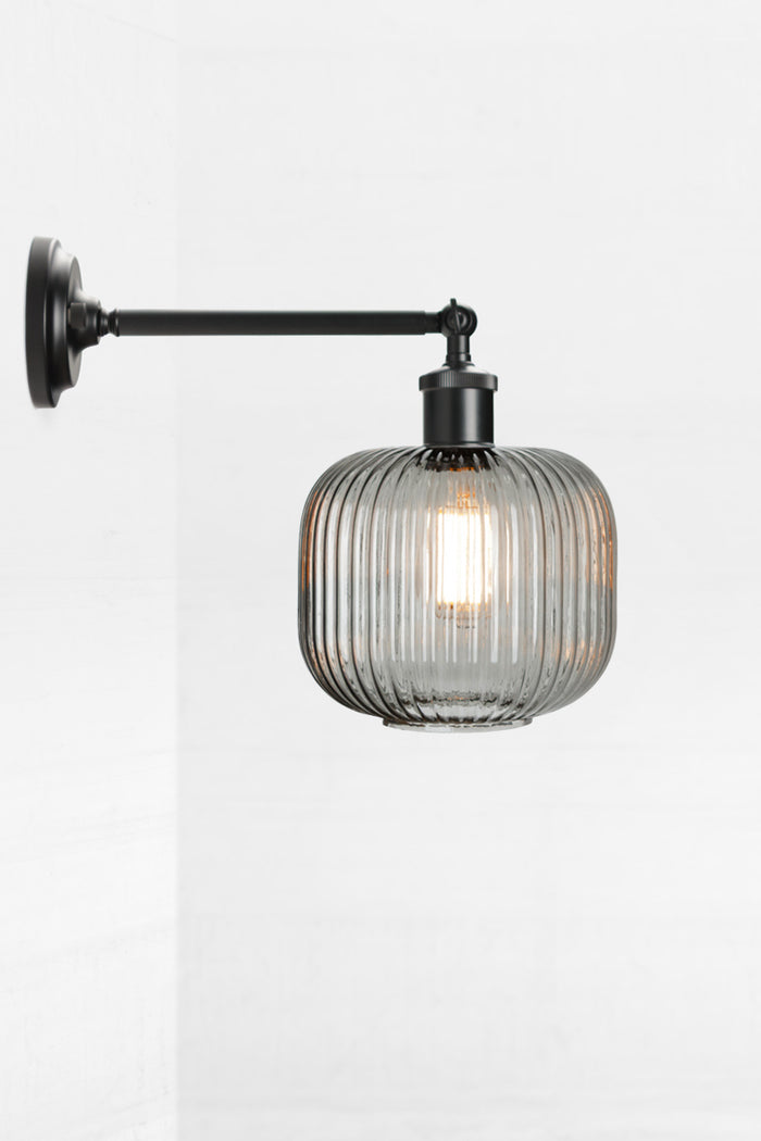 Black swivel wall sconce with long arm and a reeded glass shade in grey.