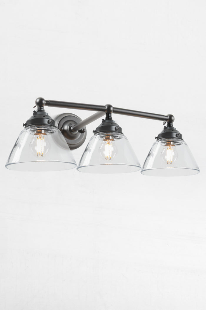 Swivel lampholders for directional lighting on Black triple lamp wall sconce with the clear glass shades.