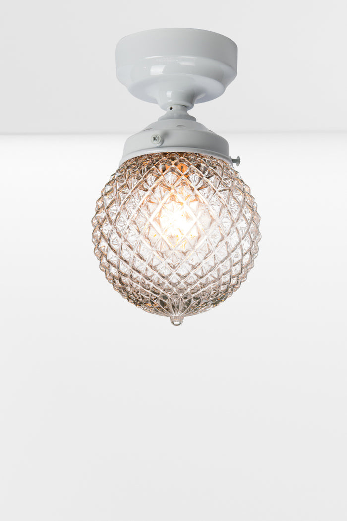 Clear glass ball shade with vintage detailing on a white batten holder.