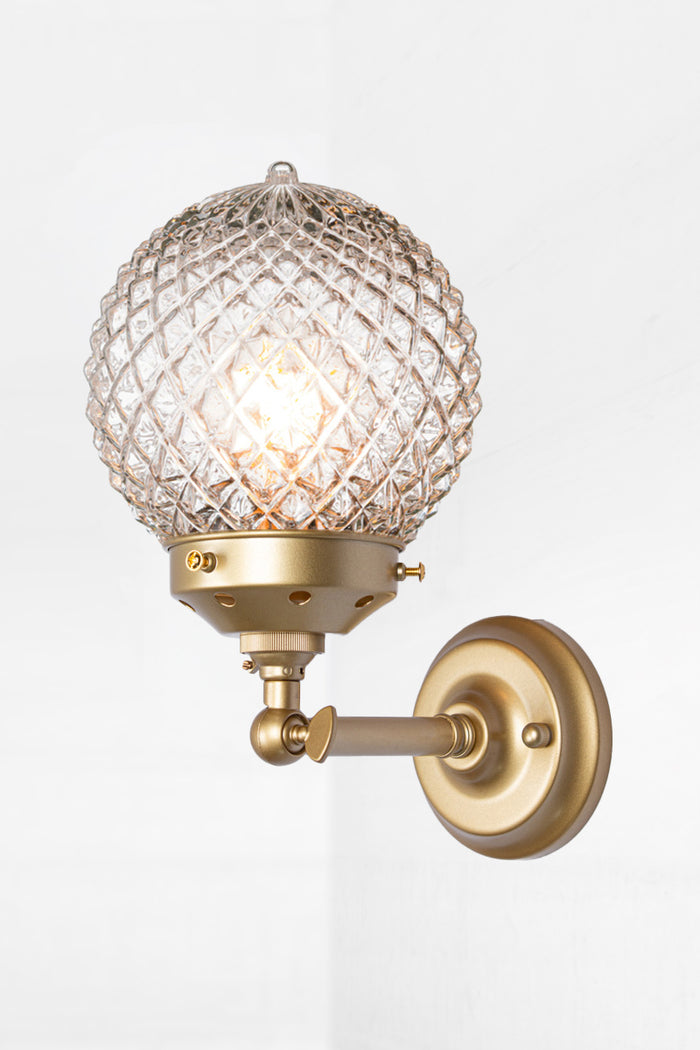 Vintage detailed, clear, glass orb shade on a short straigh wall sconce in gold/brass with a swivel lampholder.