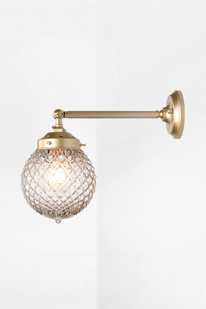 Vintage detailed, clear, glass orb shade on a long straigh wall sconce in gold/brass with a swivel lampholder.