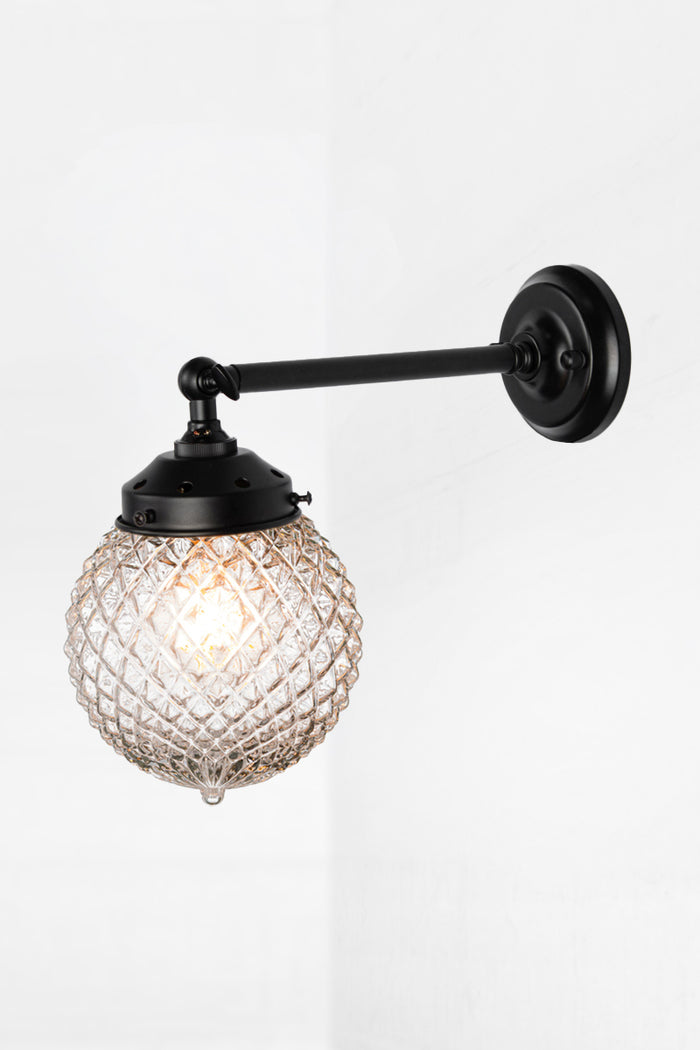 Vintage detailed, clear, glass orb shade on a long straigh wall sconce in black with a swivel lampholder.