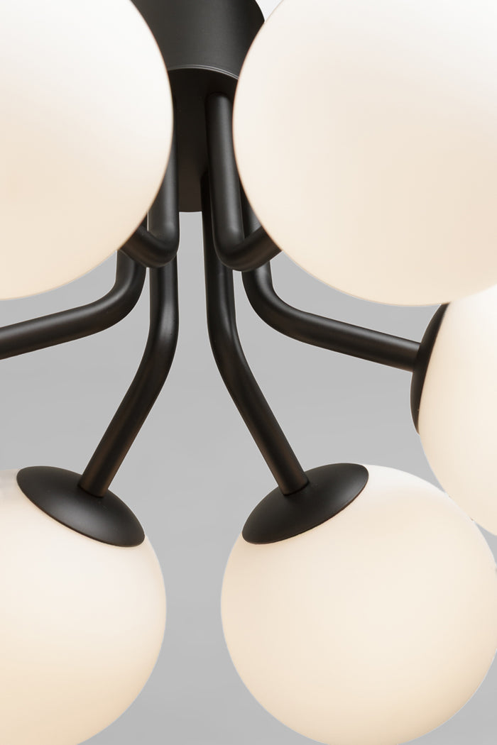 Close-up of a modern multi-light chandelier with matte black metal arms and glass orbs in opal glass finish