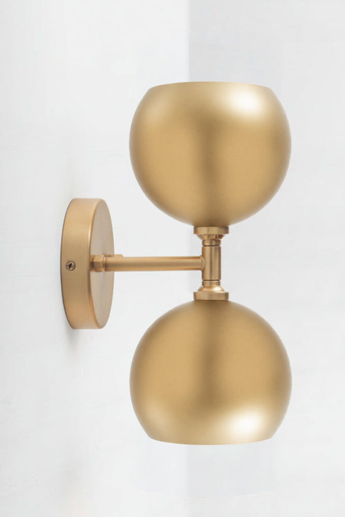 Gold double wall sconce with two steel bulb shades in gold.