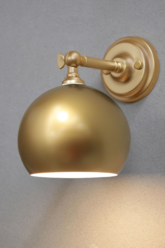 Gold short, straight wall sconce with a gold bowl shade.
