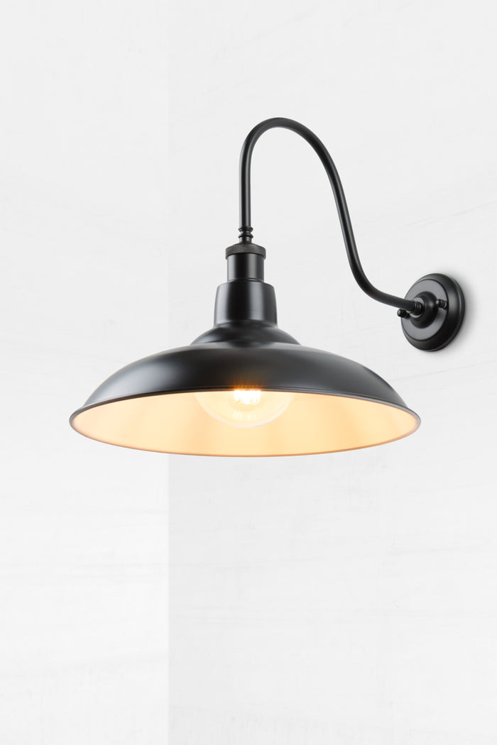 Black metal shade with an extra large gooseneck outdoor wall sconce and round clear bulb.