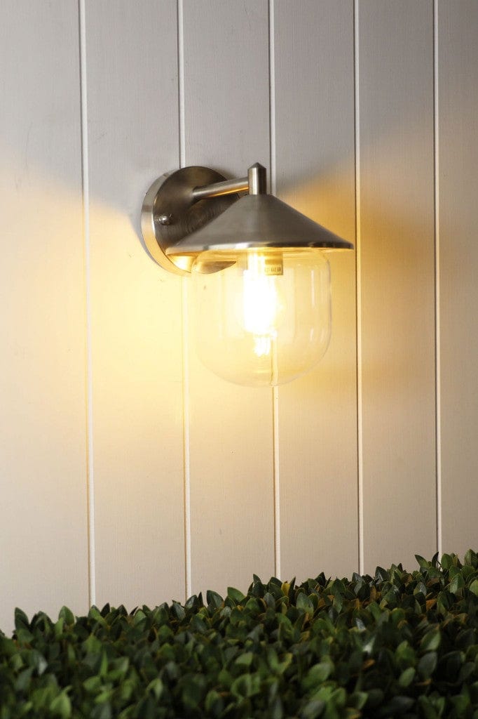 Stainless steal variant of Cabin Outdoor Wall Light affixed on white wooden panel wall
