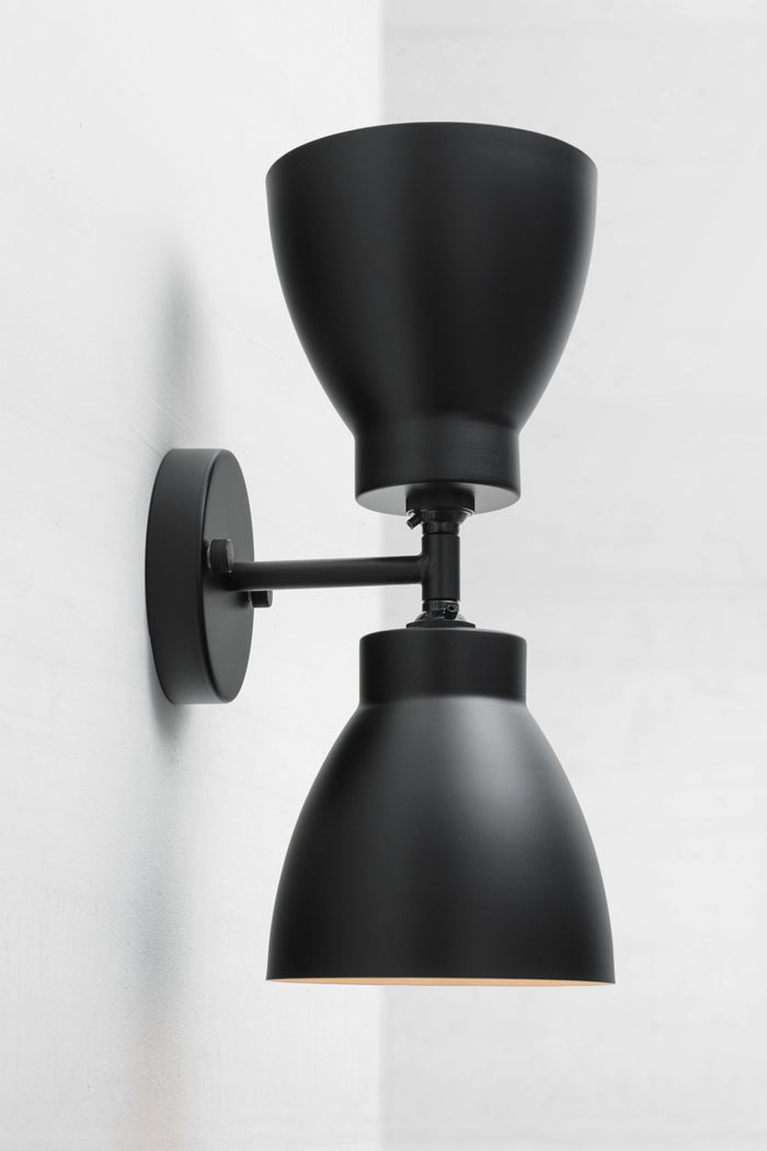 Black double wall sconce with two black metal shades.