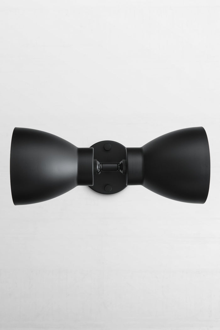 Black double wall sconce with two black metal shades, installed sideways.