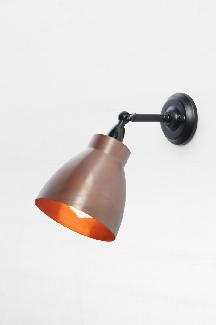 Solid copper celler shade on a short black outdoor wall sconce.