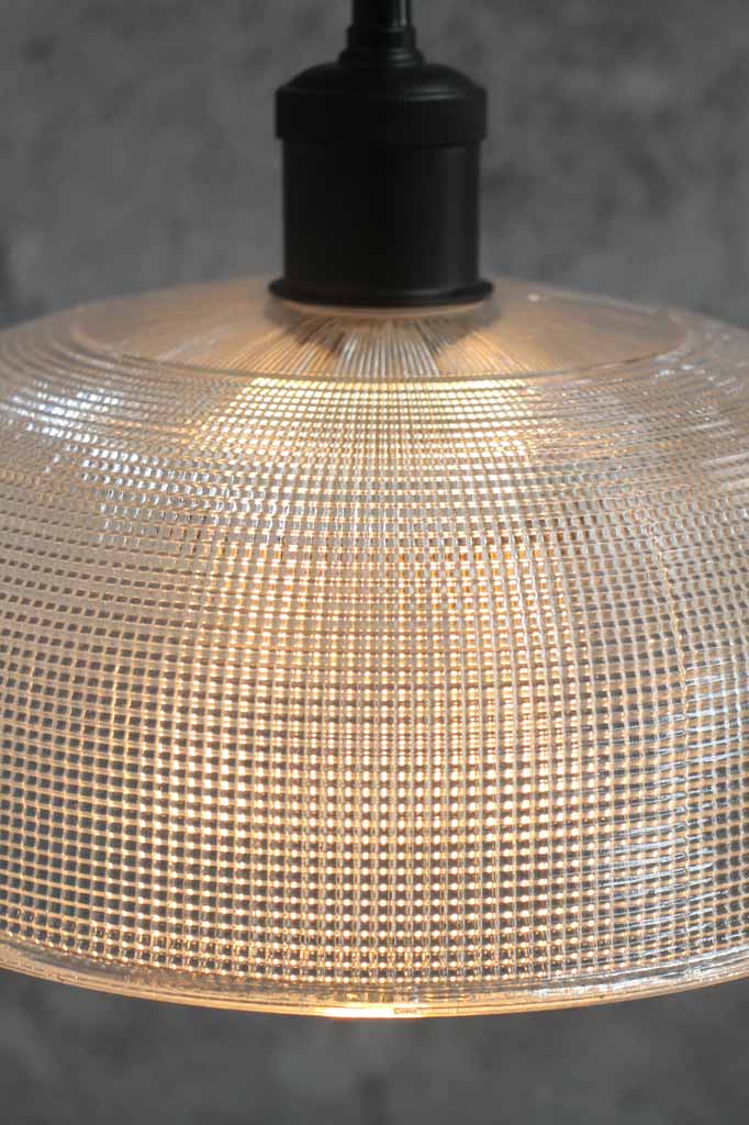 Close up of the clear large shade on a black pendant cord.