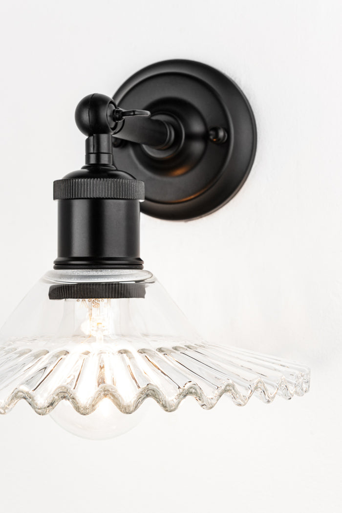 Close up of the clear glass shade with frill edge on the short black swivel wall sconce.