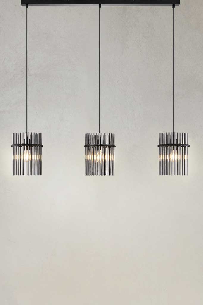 Three light pendant hanging on a black ceiling mount with smoke glass rod shades.