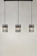 Three light pendant hanging on a black ceiling mount with smoke glass rod shades.