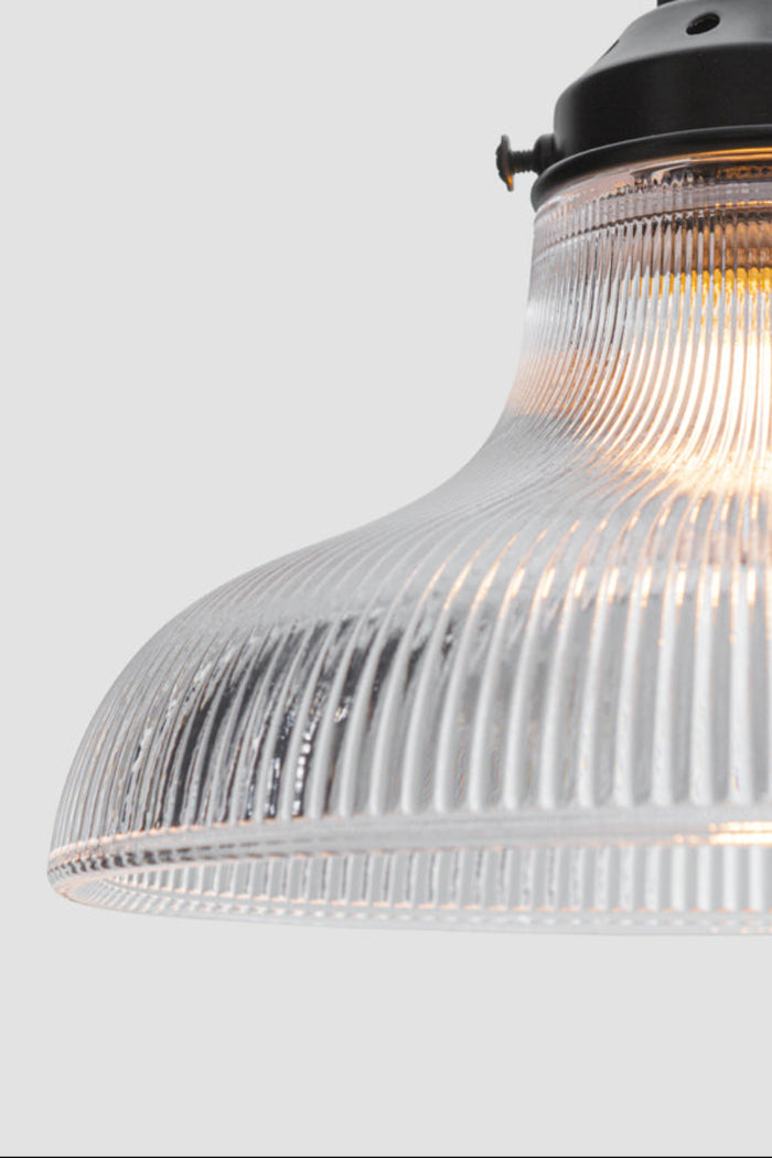 Close up of the small clear holohpane glass shade on a black gallery