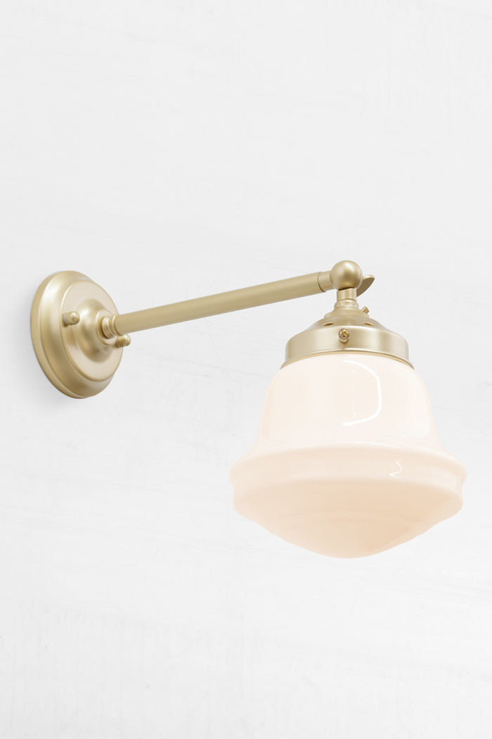 Opal schoolhouse style shade on a long, gold/brass, straight arm wall sconce.