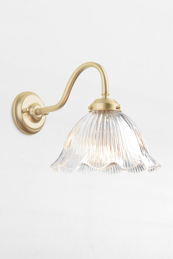 Gold/Brass gooseneck outdoor wall light with a clear glass shade that has a ribbed detiling and frill edge.
