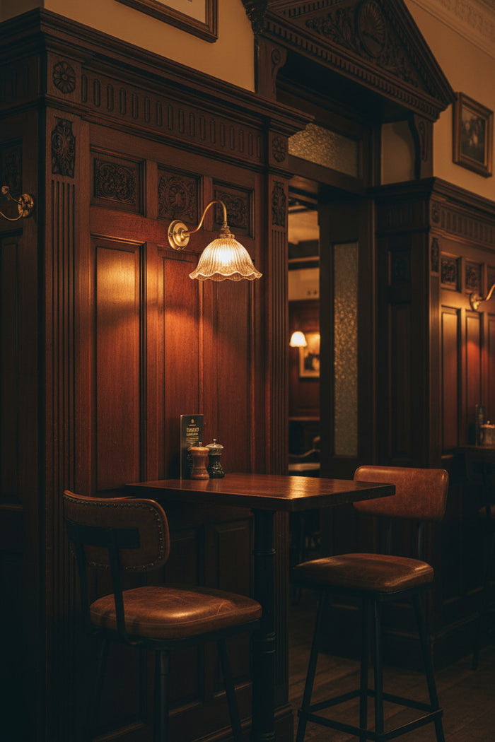 Dark bar interior with wooden walls, a table, and chairs under warm lighting; oour Gold/brass gooseneck arm