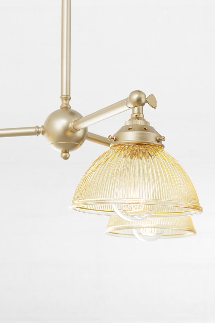 Close up of the amber glass reeded shades with a plain edge, paired with a gold/brass fixture.