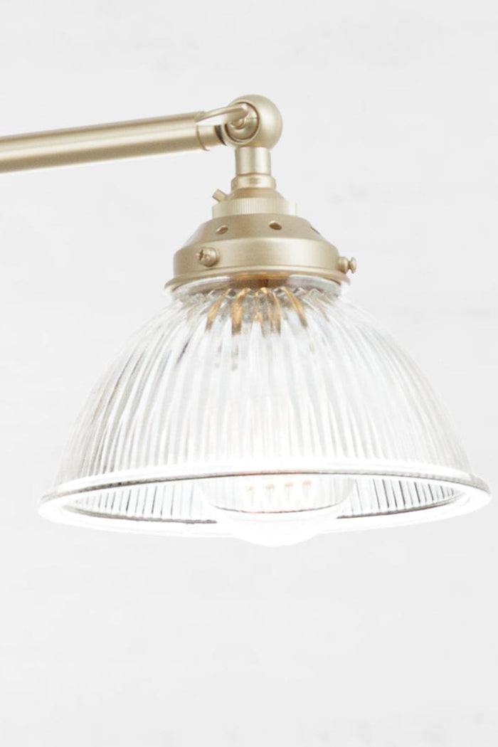 clear glass shade paired with a gold/brass finished triple arm fixture.