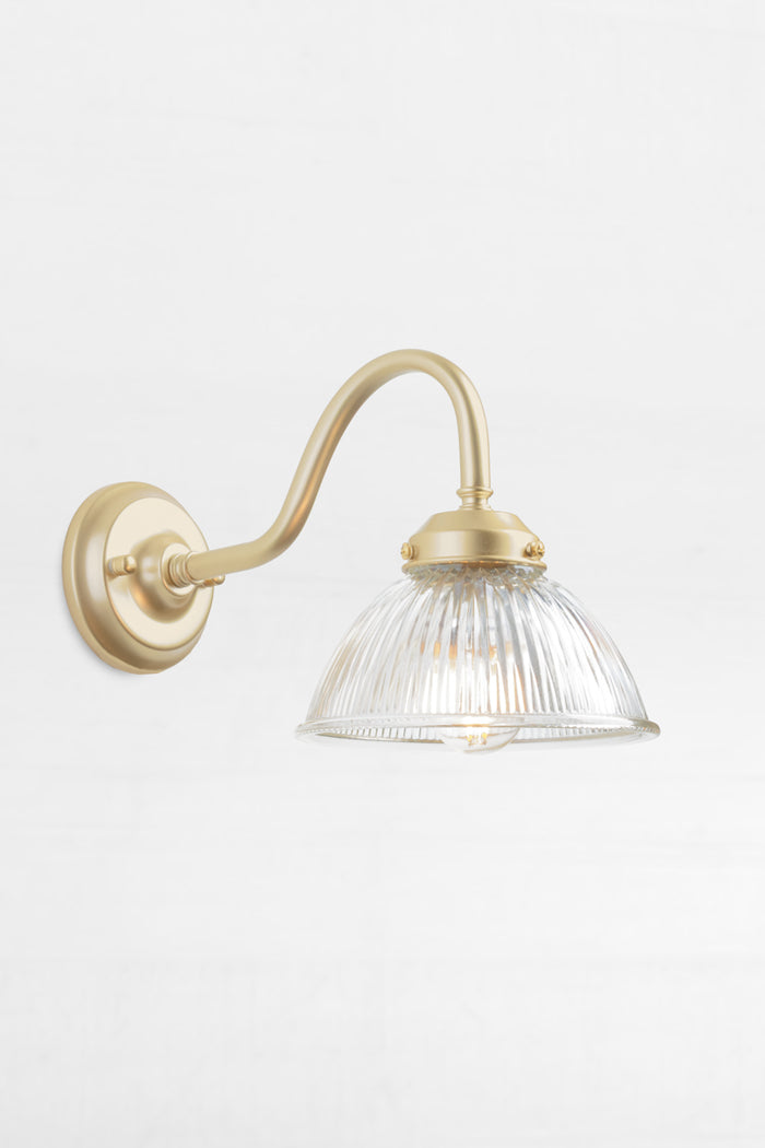 Gold/brass outdoor gooseneck wall light with a clear ribbed shade.