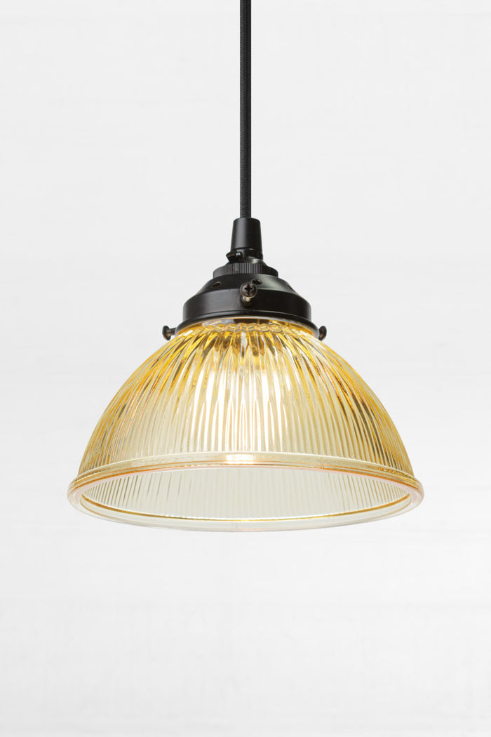 Amber glass shade with reeded detailing on a black pendand cord